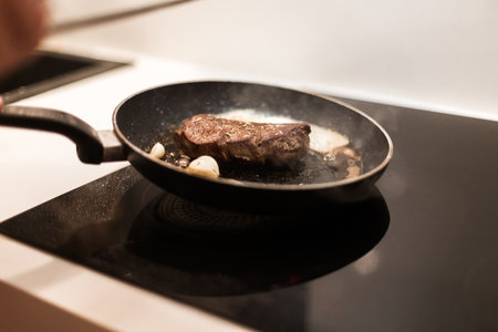 the process of cooking beef steak in a frying pan with butter and rosemaryの写真素材