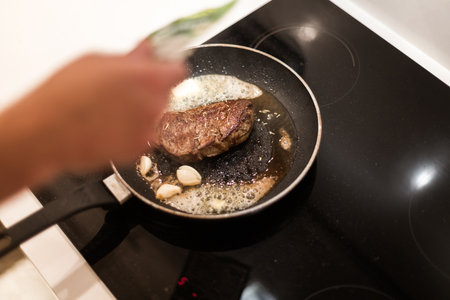 the process of cooking beef steak in a frying pan with butter and rosemaryの写真素材