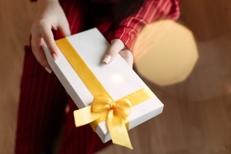 girl in red pajamas holding christmas present in white box and phone insideの写真素材