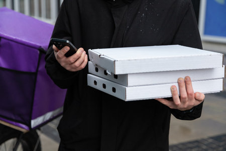 courier on a bicycle courier on a bicycle looks at the map on his phone and looks for an address to deliver an orderの写真素材