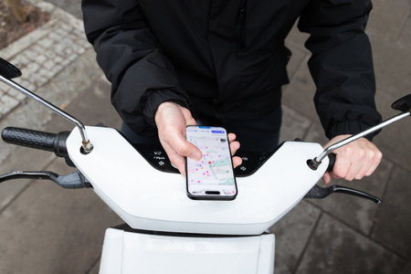 courier on a courier on a scooter looks at the map on his phone and looks for an address to deliver an orderの写真素材