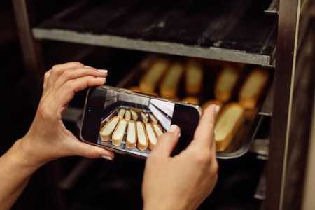 This picture is for todays online baking tips. Cropped shot of a female baker taking a picture on her cellphone of a selection of freshly baked bread.
