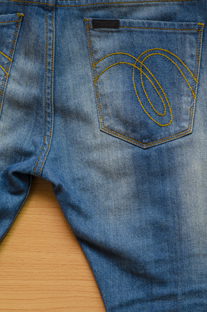 Blue denim with seam and Jeans pocket on wood backgroundの写真素材