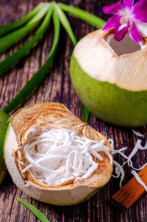Coconut flesh in half coconut shell on a wooden floor with fresh coconut ready to serve.の写真素材