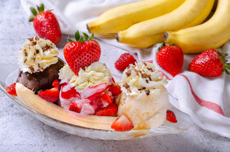 Sweet homemade banana split sundae with chocolate vanilla and strawberry ice cream on glass bowl,...