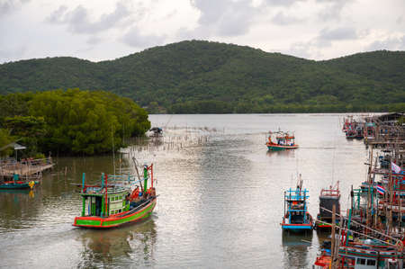 Thai fishing boats are sailing out to sea in the evening at sunset.