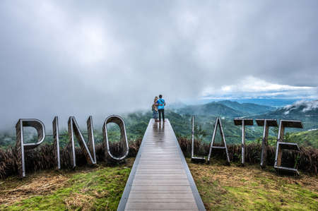 Wooden bridge walkway extending to the cliff. View of mountain waves and morning mist At the viewpoint labeled "PINO LATTE" at Thailand.の写真素材