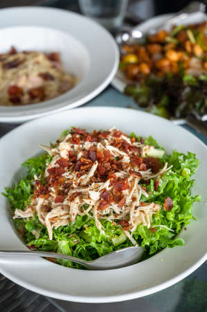 Salad with bacon and chicken, cesar salad background. lettuce salad close-up on a plate on a table.の写真素材