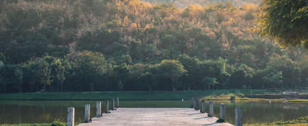 Pier on the lake, wooden bridge in the forest during spring with a lake for fishing and misty hills in the morning at Kanchanaburi, Thailand.の写真素材