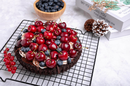 Delicious  Dark chocolate tart with cherries and blueberries on the black rack. Close up.