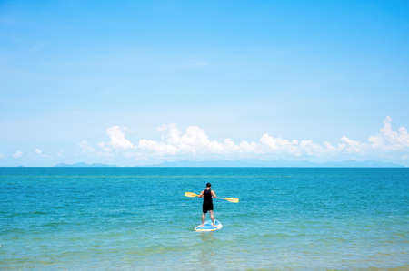 Man stand up paddleboarding on ocean. Man are doing water sport on sea. Male tourists are in...