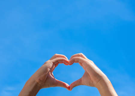 Hands making shape of heart against the sky. Love, friendship concept.の写真素材