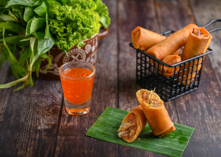 Deep fried spring rolls cut in half served with special sauce a variety of vegetables.の写真素材