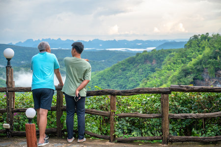 Asian male Two tourists looking at the mountain view and fog in the morning at canyon Nam Nao in...