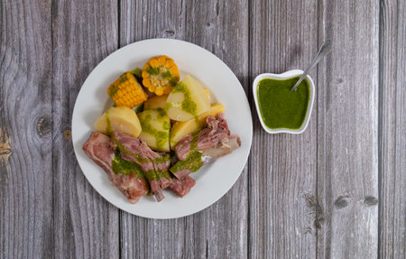 Top view of Food from the Canary Islands (Spain), consisting of a dish of salty ribs, boiled potatoes with ears of sweet corn covered with spicy green mojoの写真素材