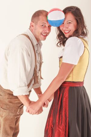 Bavarian couple in love laughing when playing with a ballの写真素材