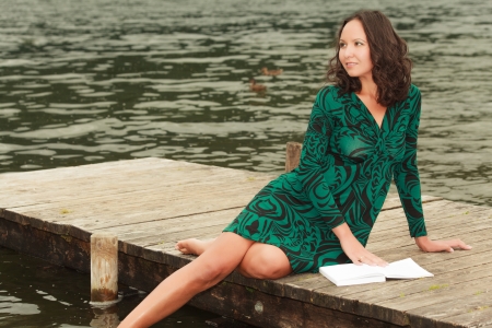 Attractive woman is recovering at the lake while readingの写真素材