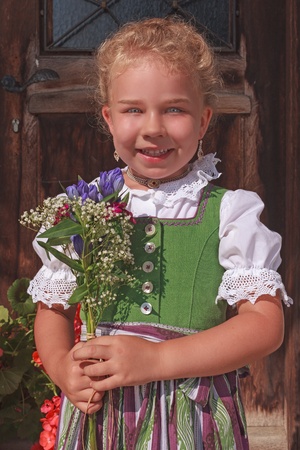 Portrait of a little girl in dirndl with a bouquetの写真素材