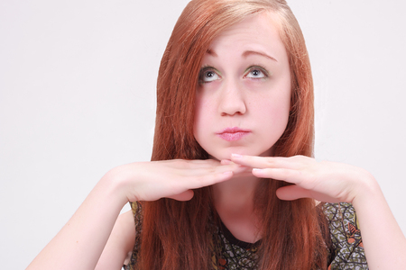 Woman with both hands under her chin looking cute on white backgroundの写真素材