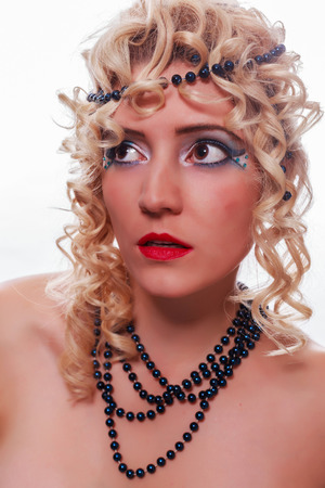 Young woman with pretty face and shirtless, with black pearl necklace around her neck and in her blond curly hair.の写真素材