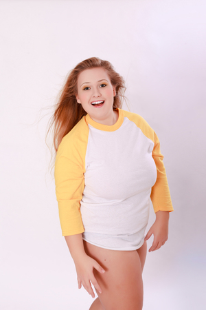 Young curvy blonde girl with long hair, wearing only a long sleeve shirt, laughing at the camera - Three Quarter Lengthの写真素材