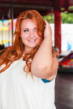 Portrait of a young, smiling plus size woman with long red hair.の写真素材