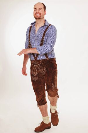 Young Bavarian man in leather pants dancing and hitting the thighの写真素材