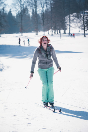 Red-haired young woman has fun with cross-country skiing in the Alps.の写真素材
