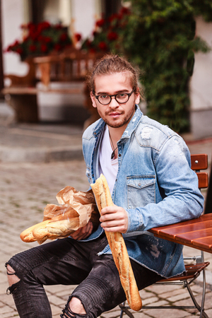 Young man eating a baguette at the same time.の写真素材