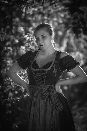 Portrait of a Bavarian girl in a dirndl on an apple tree in black and whiteの写真素材