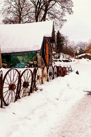 Old wooden barn in winter with old iron cart wheelsの写真素材