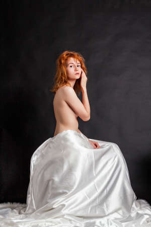 Young girl with red hair, hides her breasts with her arm.の写真素材
