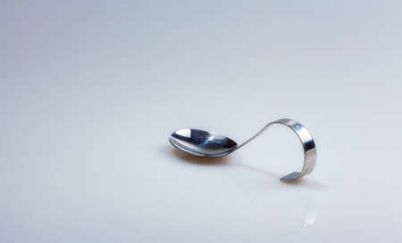 A silver spoon with curved handle photographed half sideways isolated on whiteの写真素材