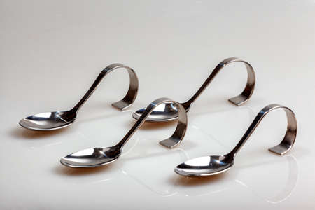 four silver spoons with curved handle photographed half sideways, placed inside each other and isolated on whiteの写真素材