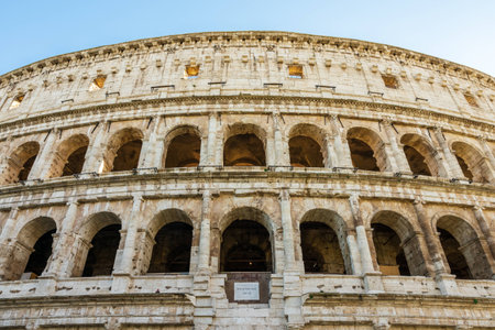 Zoom in closeup front view of ancient Colosseum amphitheater thatâs fill up almost entire frame with little blue sky as background in Rome, Italy during sunny daytime.の写真素材