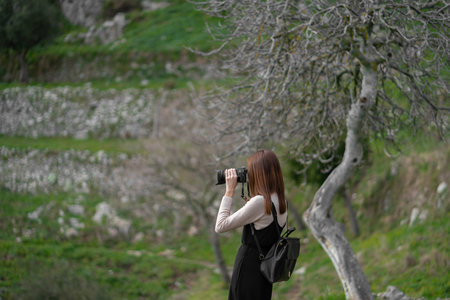 Young asian girl taking picture of the beautiful scenery while hiking along the mountain trail located at Positano, Italy.の写真素材