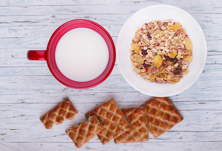 Bowl of oat flake, milk and cookies on wooden background