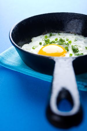 Closeup of fried eggs with greens in a cast iron panの写真素材
