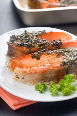 Closeup of baked trout with herbs on the white ceramic plateの写真素材