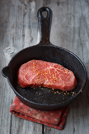 Marbled raw beef steak covered with spices in a panの写真素材