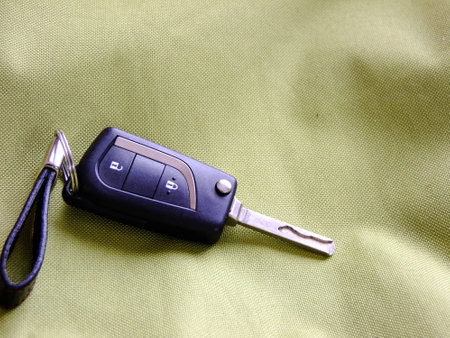 Black Car Keys opened with small Pendant on greenish Textile Backgroundの写真素材
