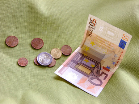Few Coins and fifty Euro Cash in greenish Textile Background