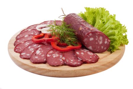 Sliced sausage with vegetables on a wooden plate isolatedの写真素材