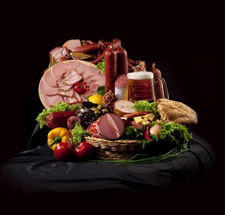 A composition of meat and vegetables with a pot full of beer on a black textileの写真素材
