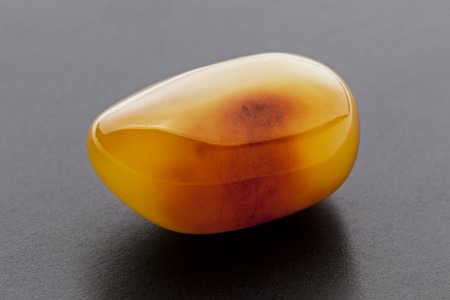 Natural amber. A piece of yellow opaque natural amber on dark grey background.の写真素材