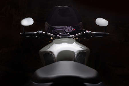 Custom caferacer motorbike on dark background with its headlight on.の写真素材