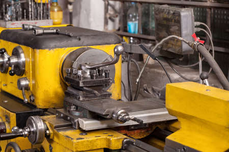 Old yellow lathe machine with a lot of handles.