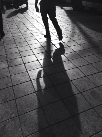 Black and white photo of a running figure with strong shadow