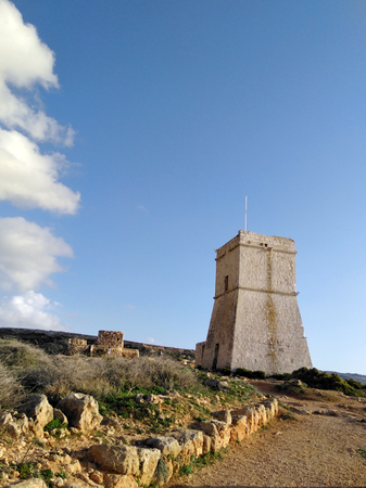 Blue sky with rocks and clouds, old guard tower on the seacost on Malta islandの写真素材