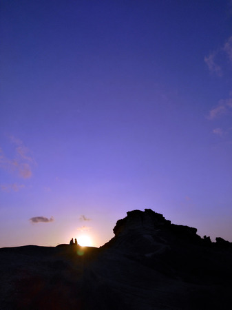 Couple - man and woman silhouette at the top of the mountain in front of sunset. Hiker rest on the rock. Background with copyspace. Symbol of romance, motivation, success, achievementの写真素材